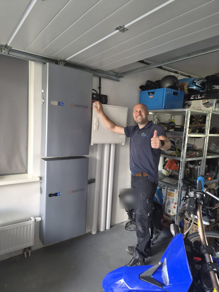 Enphase-batterijen aan de muur van een garage, met een monteur van Green-Movement